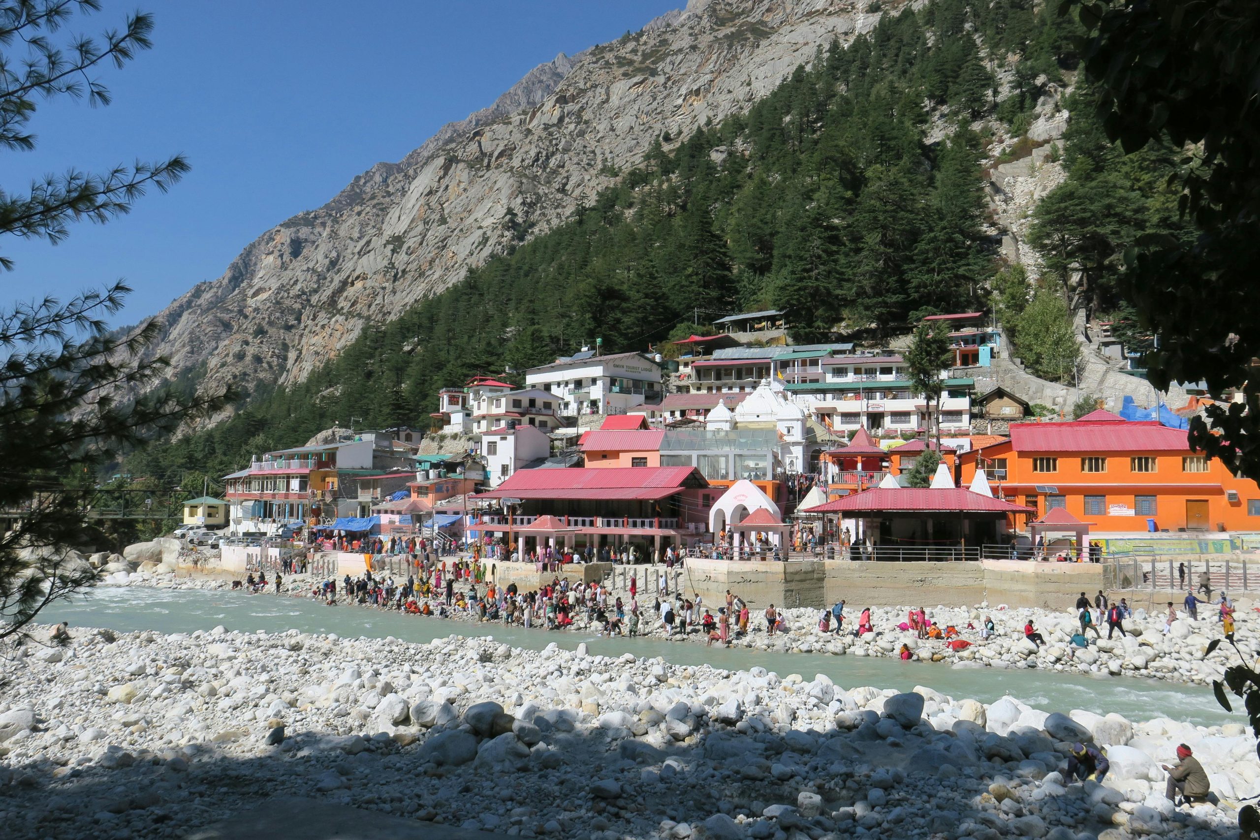Busy village scene with colorful buildings by a mountainous riverside.
